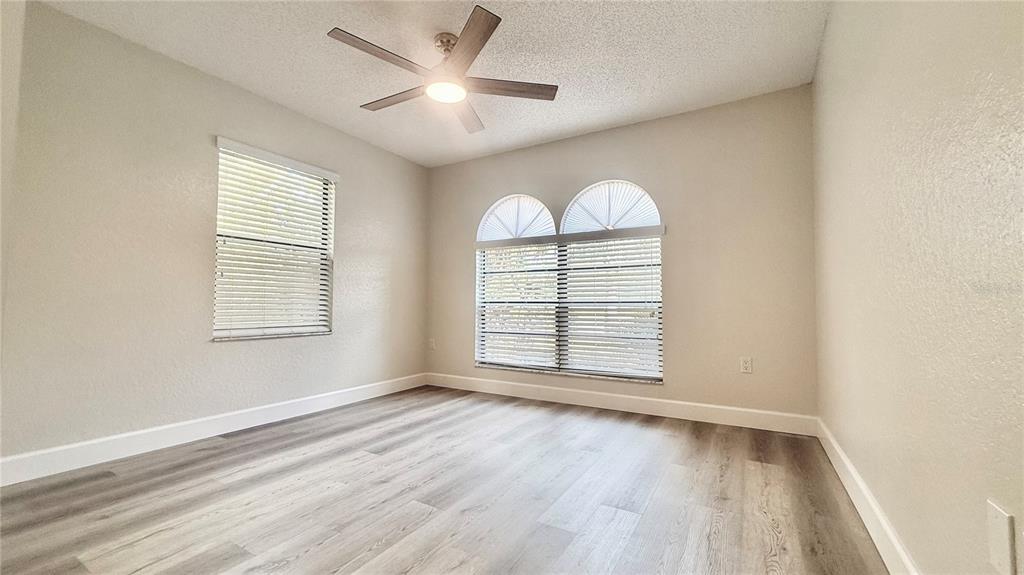 18917 Parade Road Hudson, FL 34667 - Photo 23 of 39 an empty room with wooden floor chandelier and windows