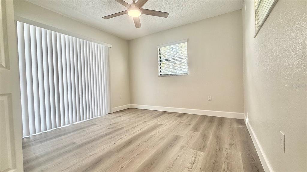 18917 Parade Road Hudson, FL 34667 - Photo 27 of 39 an empty room with wooden floor chandelier fan and windows