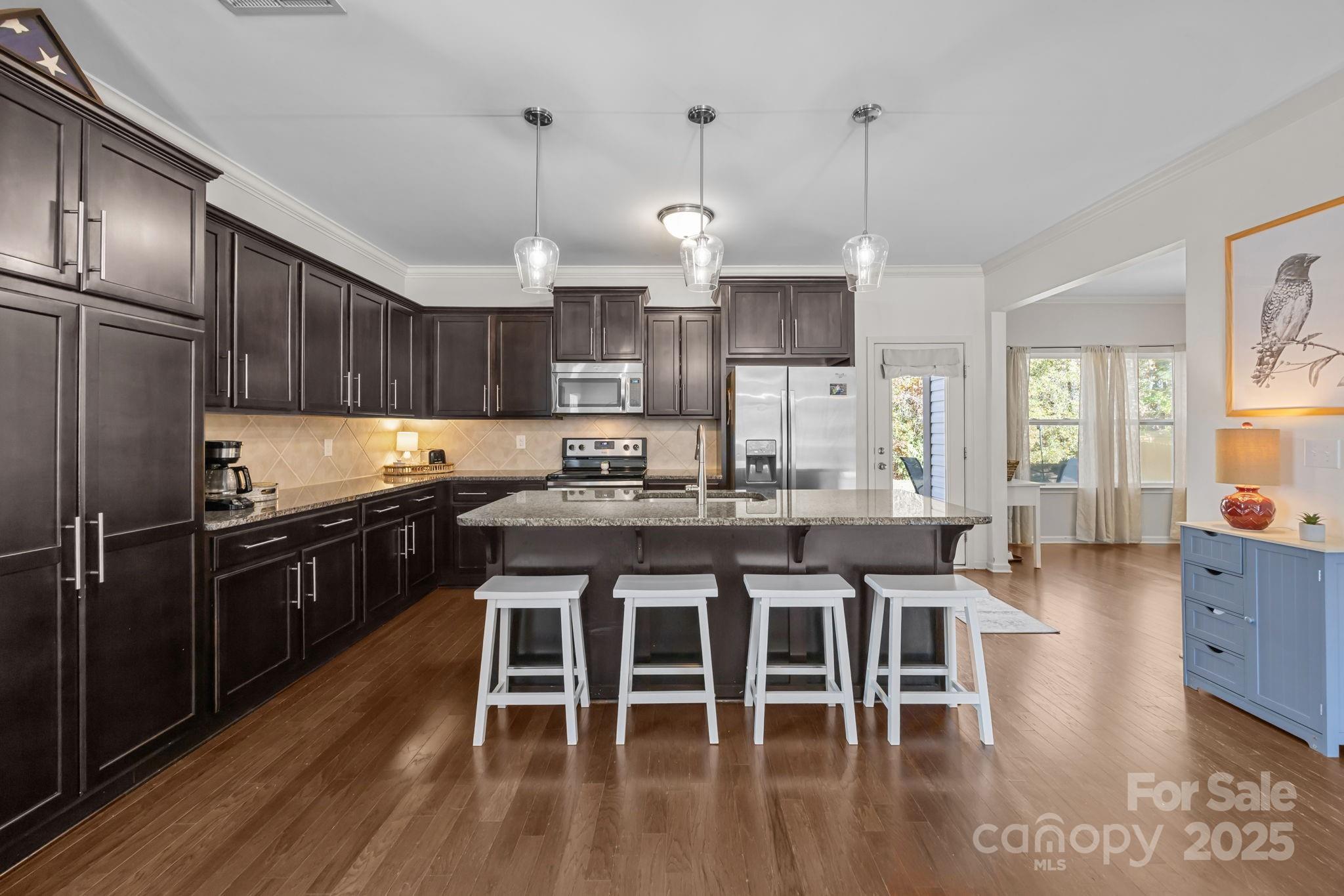 125 Devynn Ridge Court Mount Holly, NC 28120 - Photo 6 of 47 a kitchen with stainless steel appliances granite countertop a stove top oven a refrigerator a sink and a dining table with wooden floor