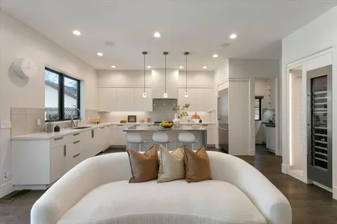 a living room with kitchen island furniture white cabinets and stainless steel appliances