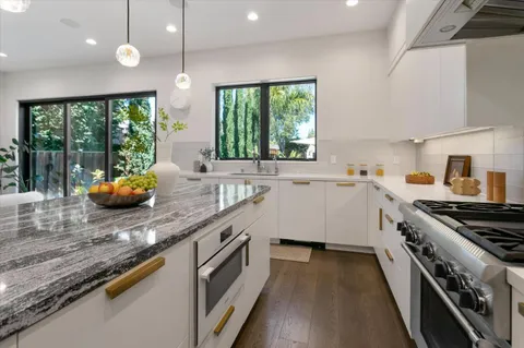 a kitchen with stainless steel appliances granite countertop a sink a stove and a wooden floor