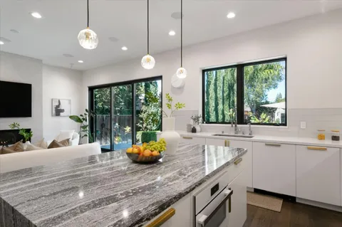 a kitchen with stainless steel appliances granite countertop a sink a stove and a wooden floors