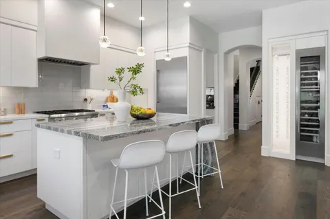 a kitchen with stainless steel appliances a sink a stove a refrigerator and island with wooden floor