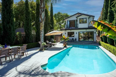 a view of a swimming pool with lawn chairs under an umbrella
