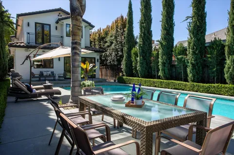 a view of a patio with table and chairs potted plants and barbeque grill with floor to ceiling window