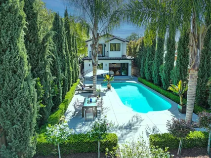a view of backyard with outdoor seating and green bushes