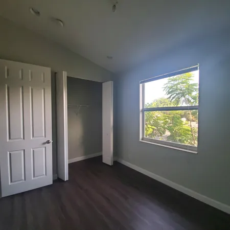 an empty room with wooden floor closet and windows