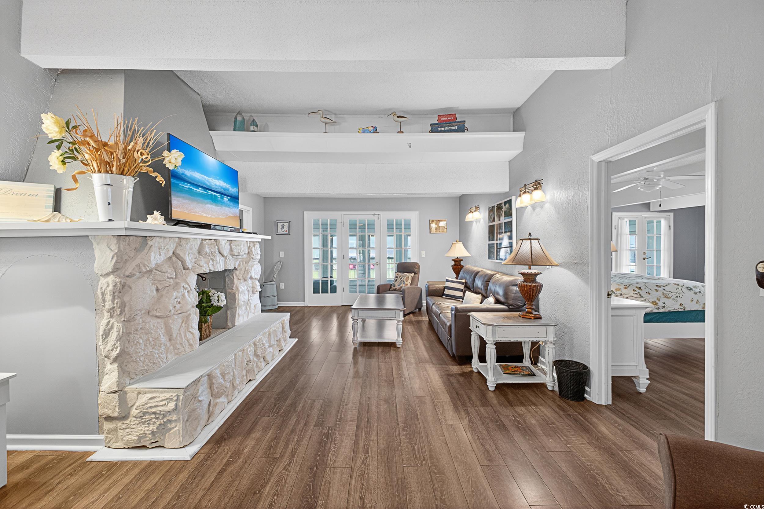 1885 Pompano Drive Murrells Inlet, SC 29576 - Photo 13 of 34 Living area featuring wood finished floors, a ceiling fan, a stone fireplace, and a textured wall