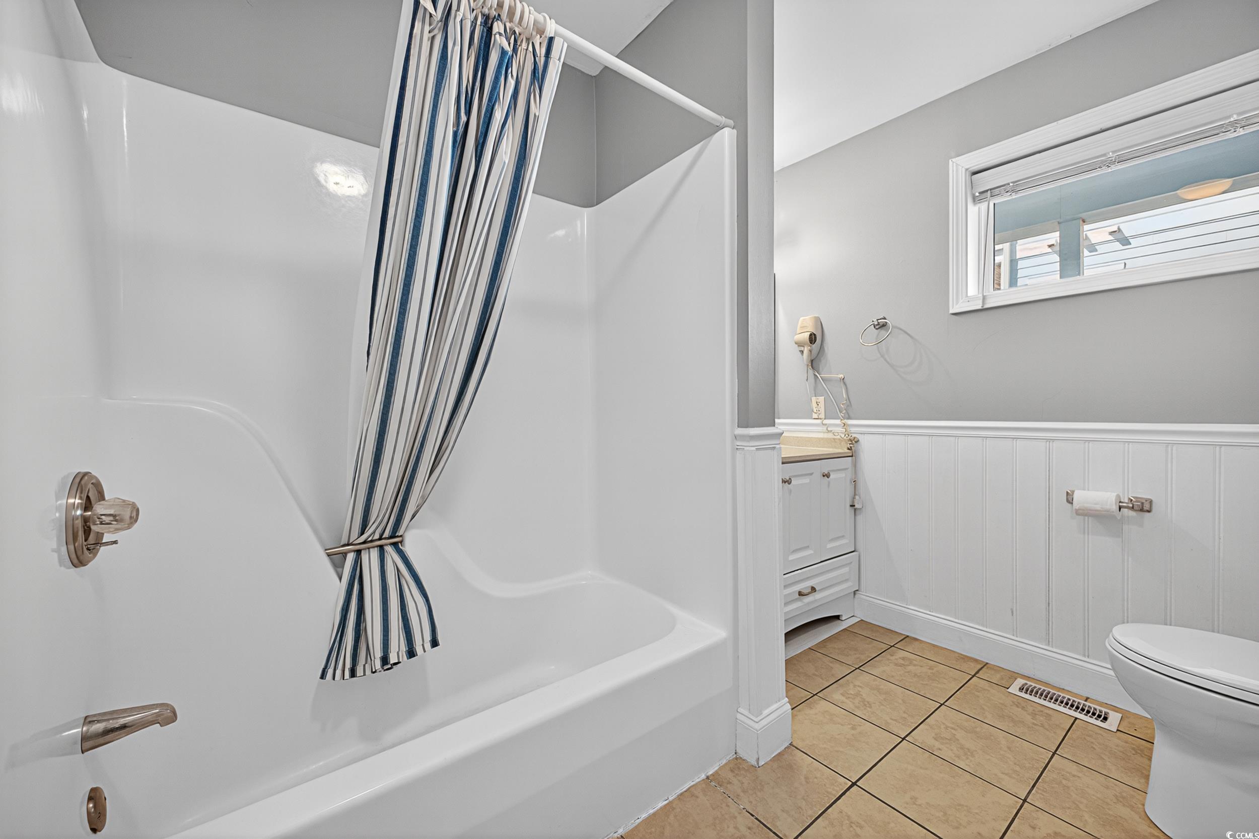 1885 Pompano Drive Murrells Inlet, SC 29576 - Photo 22 of 34 Bathroom featuring shower / bath combination with curtain, tile patterned floors, vanity, and wainscoting