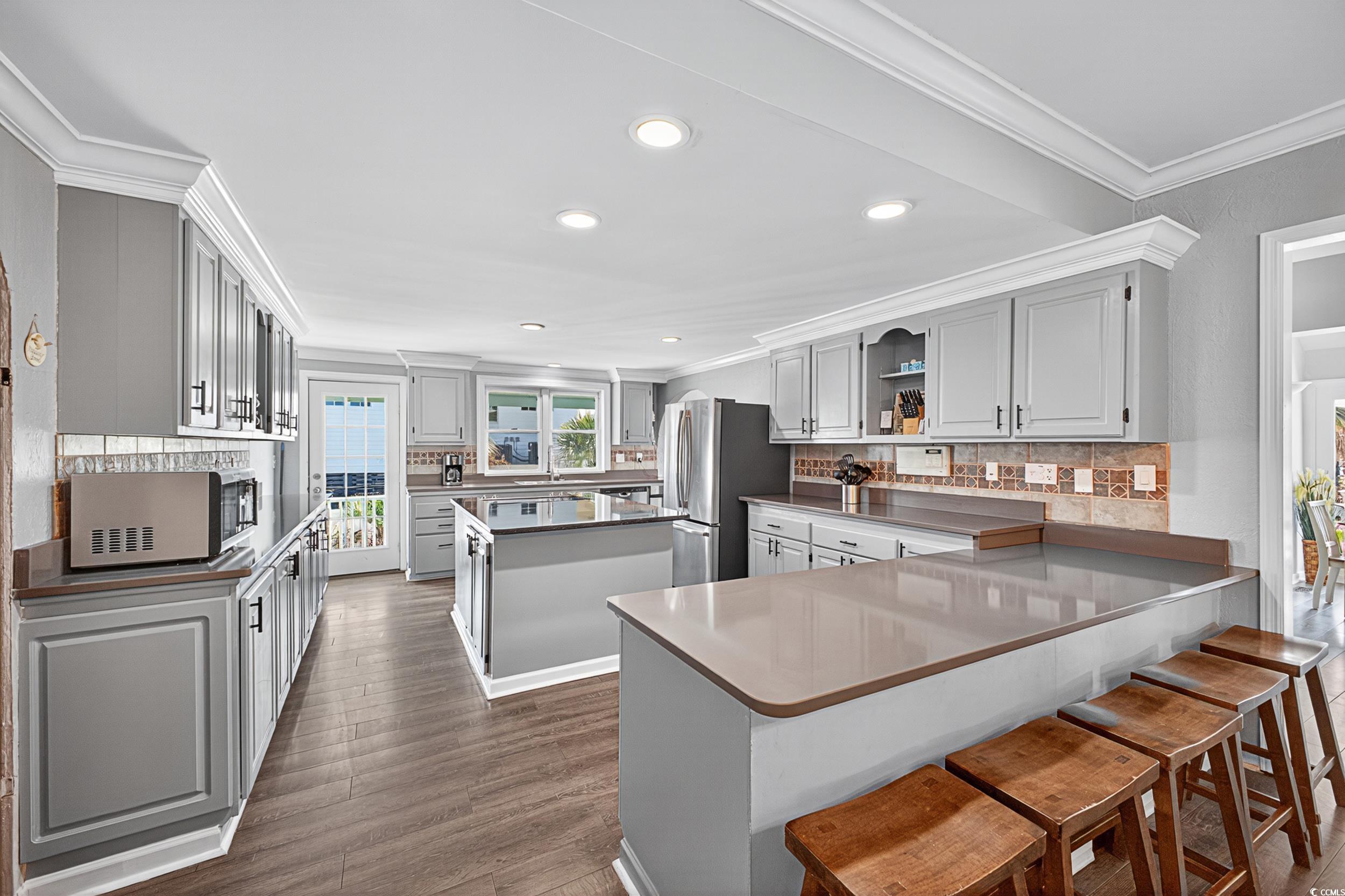 1885 Pompano Drive Murrells Inlet, SC 29576 - Photo 27 of 34 Kitchen featuring freestanding refrigerator, a kitchen island, tasteful backsplash, ornamental molding, and open shelves