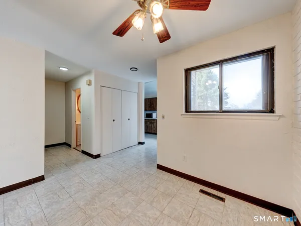 an empty room with chandelier fan and windows