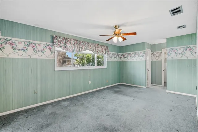 an empty room with a ceiling fan and a window