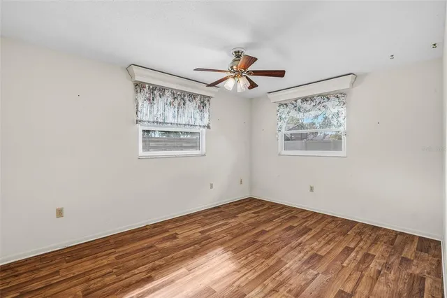 a view of a big room with wooden floor and windows