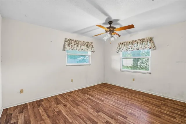 an empty room with a window and a fan