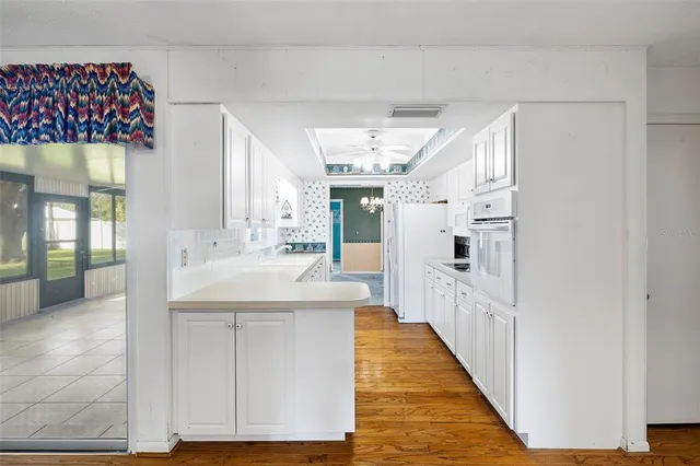 a large white kitchen with granite countertop a sink and dishwasher a refrigerator with wooden floor