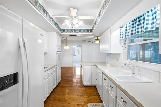 a large white kitchen with a large counter space and stainless steel appliances