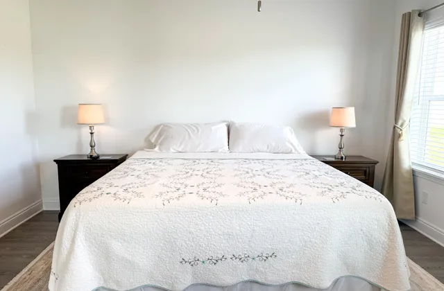 a large bed sitting in a bedroom next to a window and a lamp