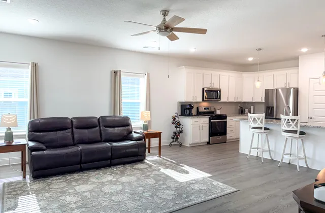 a living room with furniture kitchen area and a window