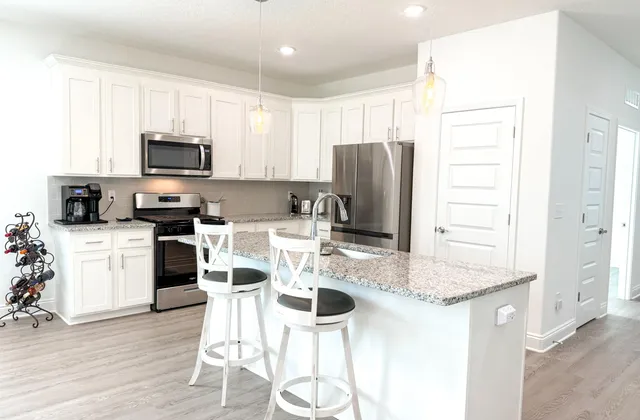 a kitchen with stainless steel appliances granite countertop a stove top oven a refrigerator a sink and a dining table with wooden floor