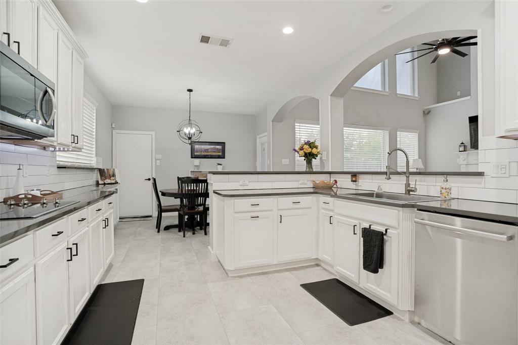 1612 Coventry Lane Allen, TX 75002 - Photo 26 of 39 Modern kitchen featuring white cabinetry, dark countertops, a subway tile backsplash, stainless steel appliances, and tile flooring