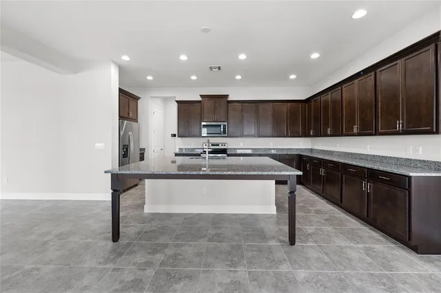 a kitchen with kitchen island granite countertop wooden cabinets a sink and a stove