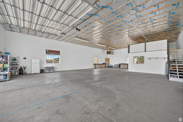 4468 North Droubay Road Tooele, UT 84074 - Photo 45 of 60 Spacious concrete flooring, high metal ceiling, multiple windows, built-in shelving, and a partial upper-level structure