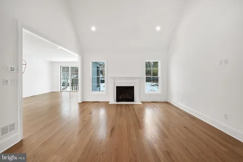 a view of an empty room with wooden floor and a fireplace