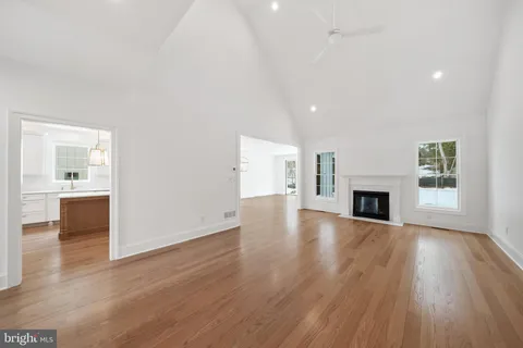 an empty room with wooden floor fireplace and windows