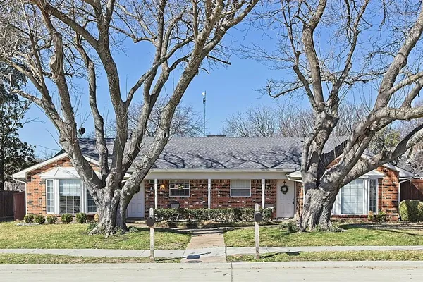 a front view of a house with garden and trees