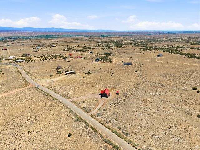 10937 South County Road, Unit 29 Duchesne, UT 84021 - Photo 37 of 41 Expansive desert landscape featuring a paved road, scattered residences, and distant mountain ranges under a clear sky
