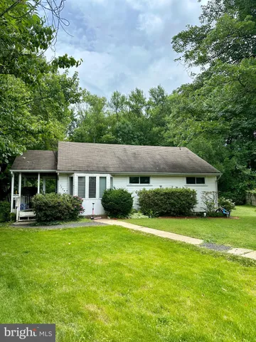 a view of a house with a big yard potted plants and large tree