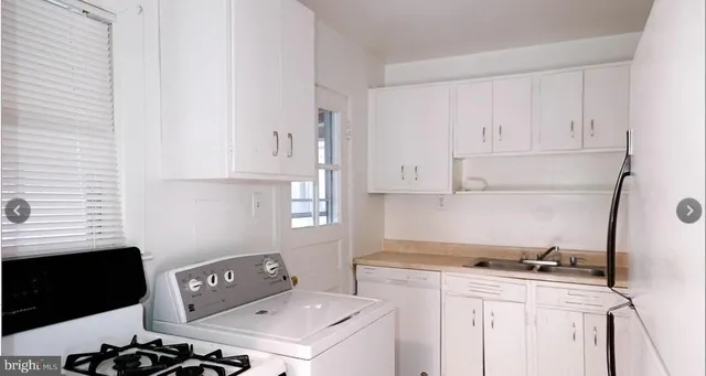 a kitchen with a sink a stove and white cabinets