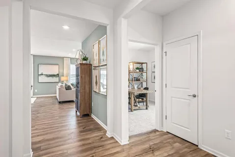 a view of a kitchen and an empty room with wooden floor and a cabinet