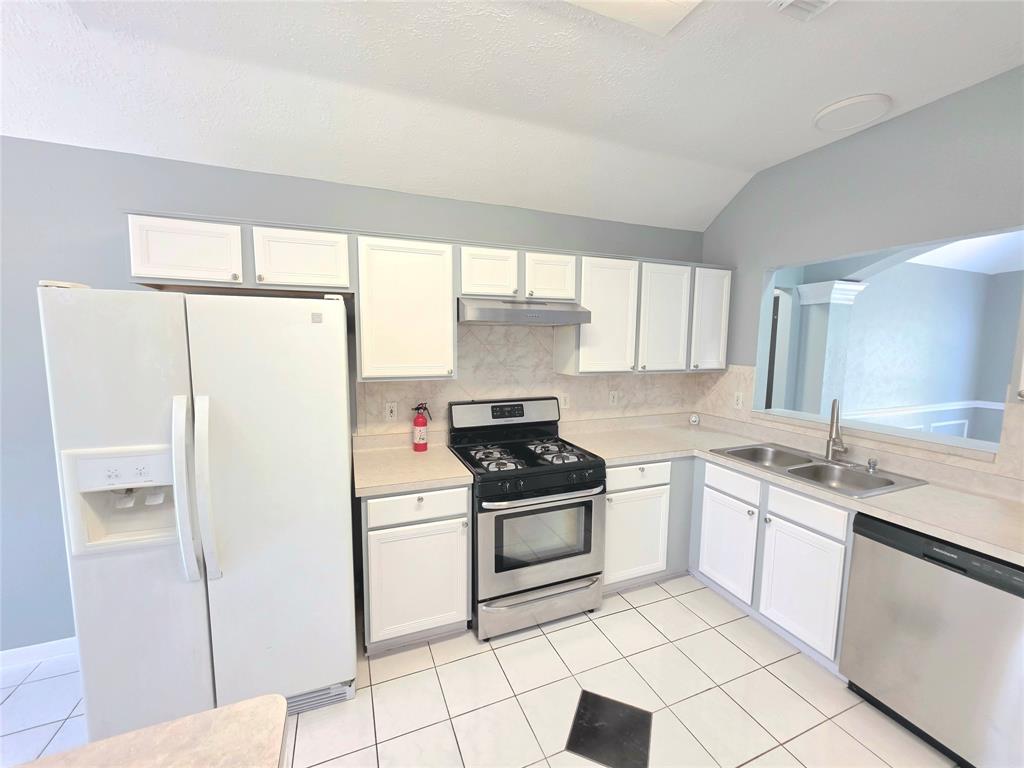 13618 Sablegrove Lane Houston, TX 77014 - Photo 6 of 30 a kitchen with a stove a refrigerator and a sink