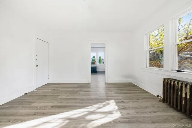 a view of an empty room and window and wooden floor