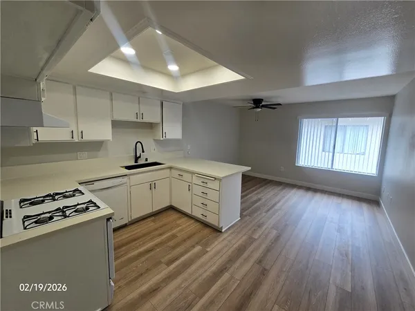 a kitchen with granite countertop a sink cabinets and wooden floor