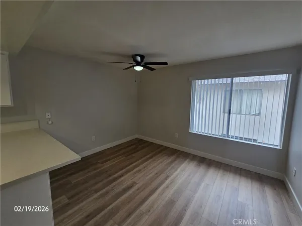 an empty room with wooden floor fan and windows