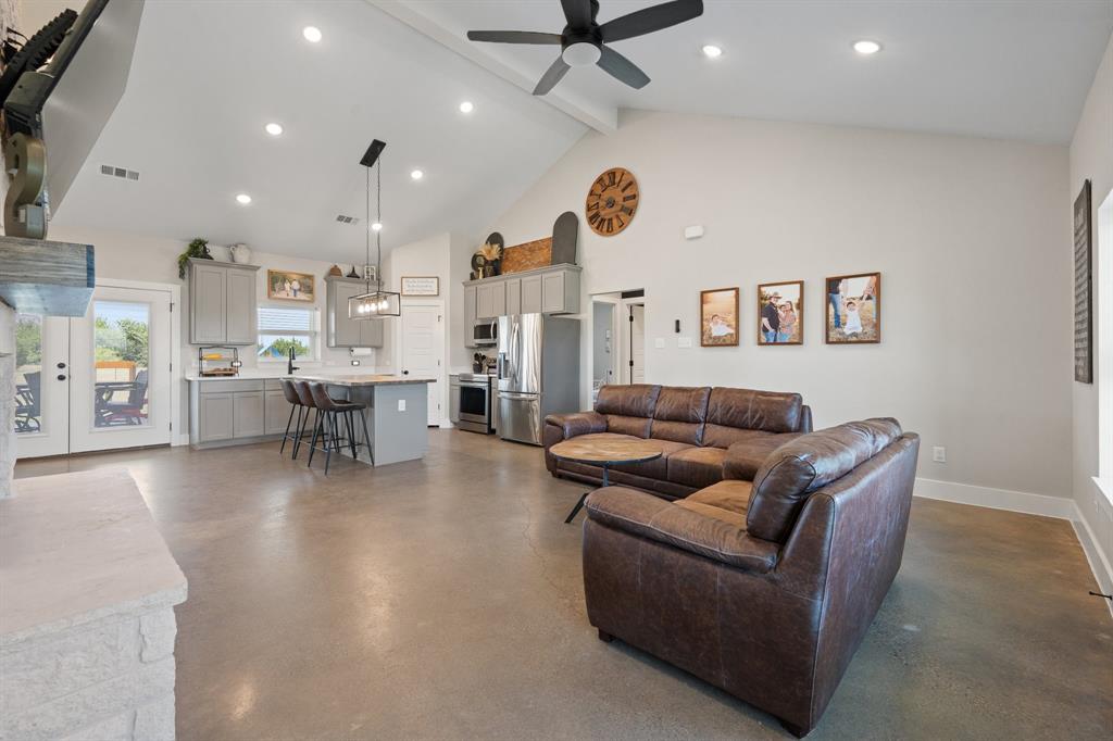 1031 Augustus Court Rio Vista, TX 76093 - Photo 3 of 30 Open-concept living space featuring vaulted ceilings, polished concrete flooring, recessed lighting, and a modern kitchen with grey cabinetry, a central island, and stainless steel appliances
