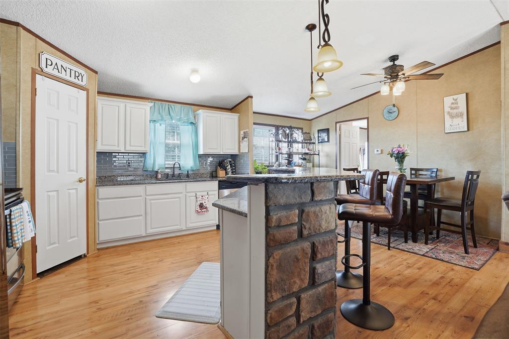 224 Cactus Ridge Court Springtown, TX 76082 - Photo 16 of 39 Kitchen with a breakfast bar area, crown molding, decorative light fixtures, white cabinets, and lofted ceiling