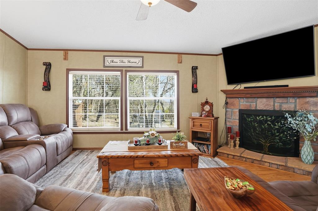 224 Cactus Ridge Court Springtown, TX 76082 - Photo 10 of 39 Living room featuring ornamental molding, a stone fireplace, wood finished floors, and a ceiling fan