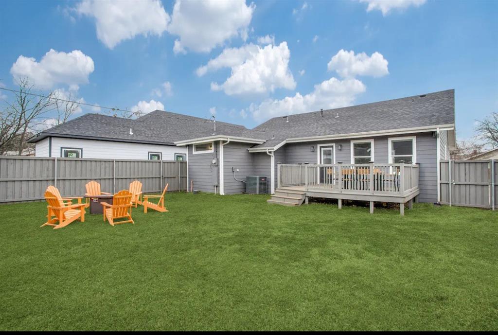 1606 West 12th Street Dallas, TX 75208 - Photo 3 of 20 Back of property featuring a fenced backyard, a wooden deck, and a shingled roof