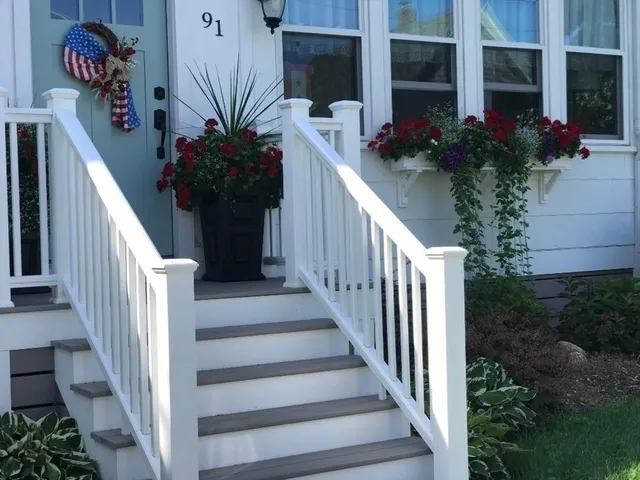 a view of a house with flower plants and wooden fence