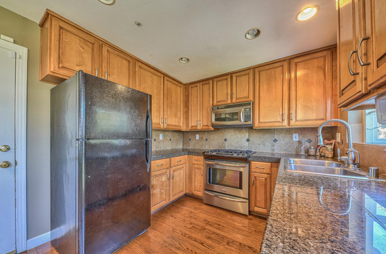 7 Grove Street Salinas, CA 93901 - Photo 12 of 33 a kitchen with stainless steel appliances granite countertop a refrigerator a sink dishwasher a stove with wooden cabinets and floor