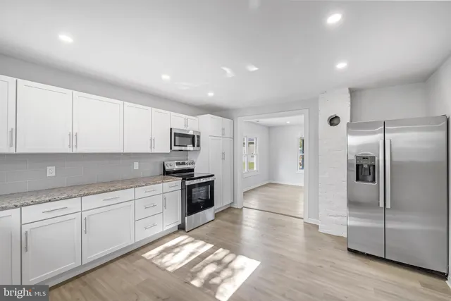 a kitchen with stainless steel appliances granite countertop a refrigerator and a stove top oven
