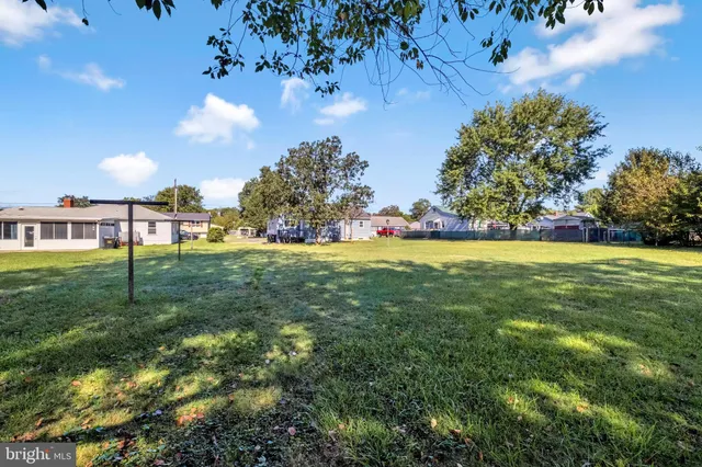 a view of yard with green space and bench in the background