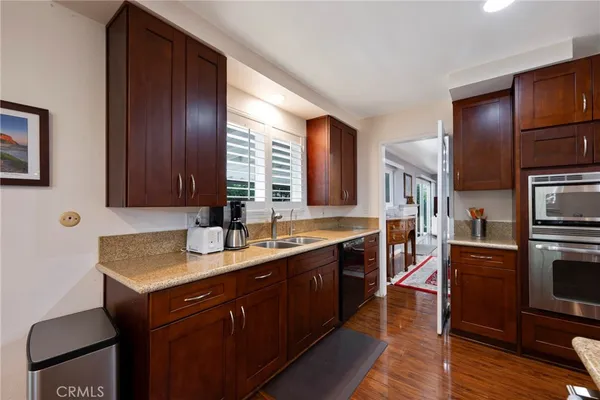 a kitchen with stainless steel appliances granite countertop wooden cabinets and a large window