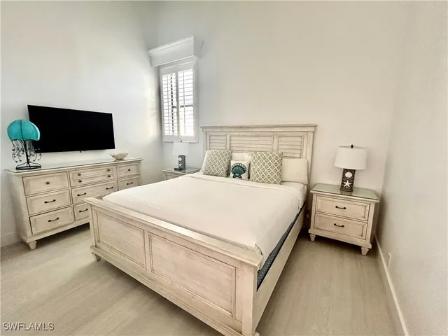 a large white bed in a white room with a flat screen tv