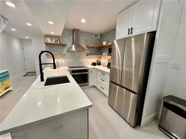 a kitchen with stainless steel appliances a refrigerator a sink a stove and white cabinets