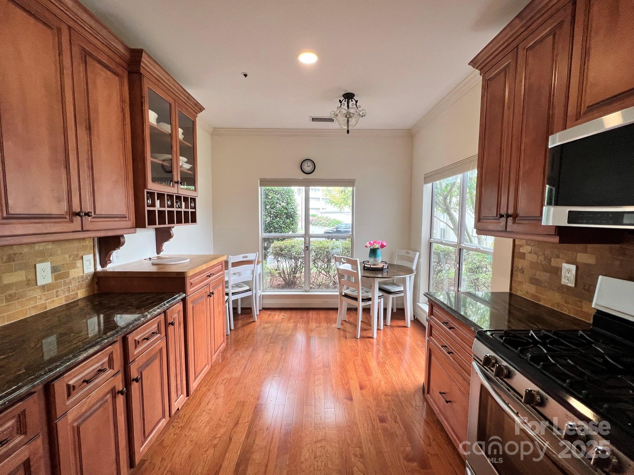 1140 Torrence Circle Davidson, NC 28036 - Photo 17 of 35 a kitchen with stainless steel appliances a stove top oven a sink dishwasher a dining table and chairs with wooden floor