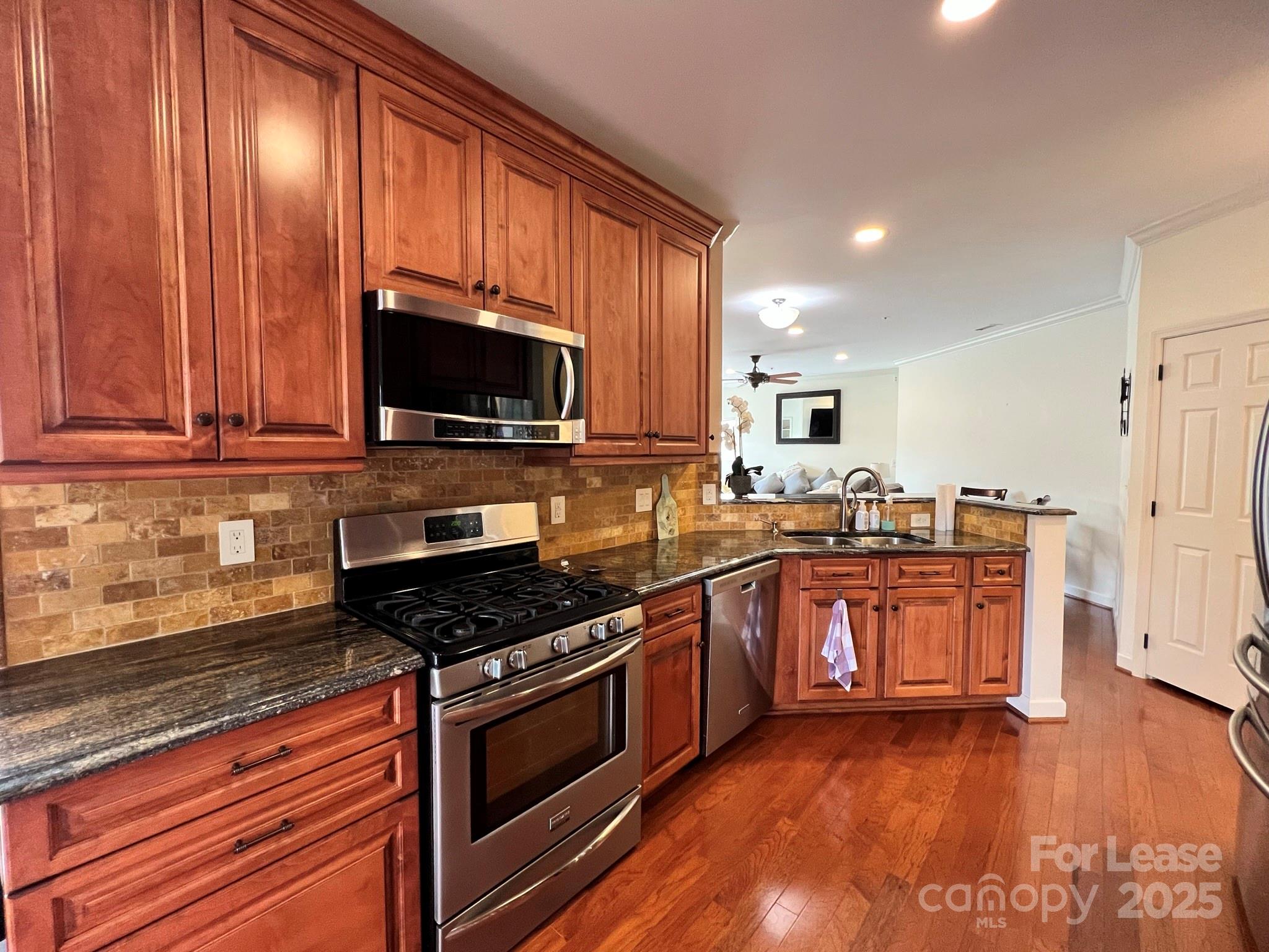 1140 Torrence Circle Davidson, NC 28036 - Photo 19 of 35 a kitchen with stainless steel appliances granite countertop wooden cabinets a stove top oven a sink and dishwasher